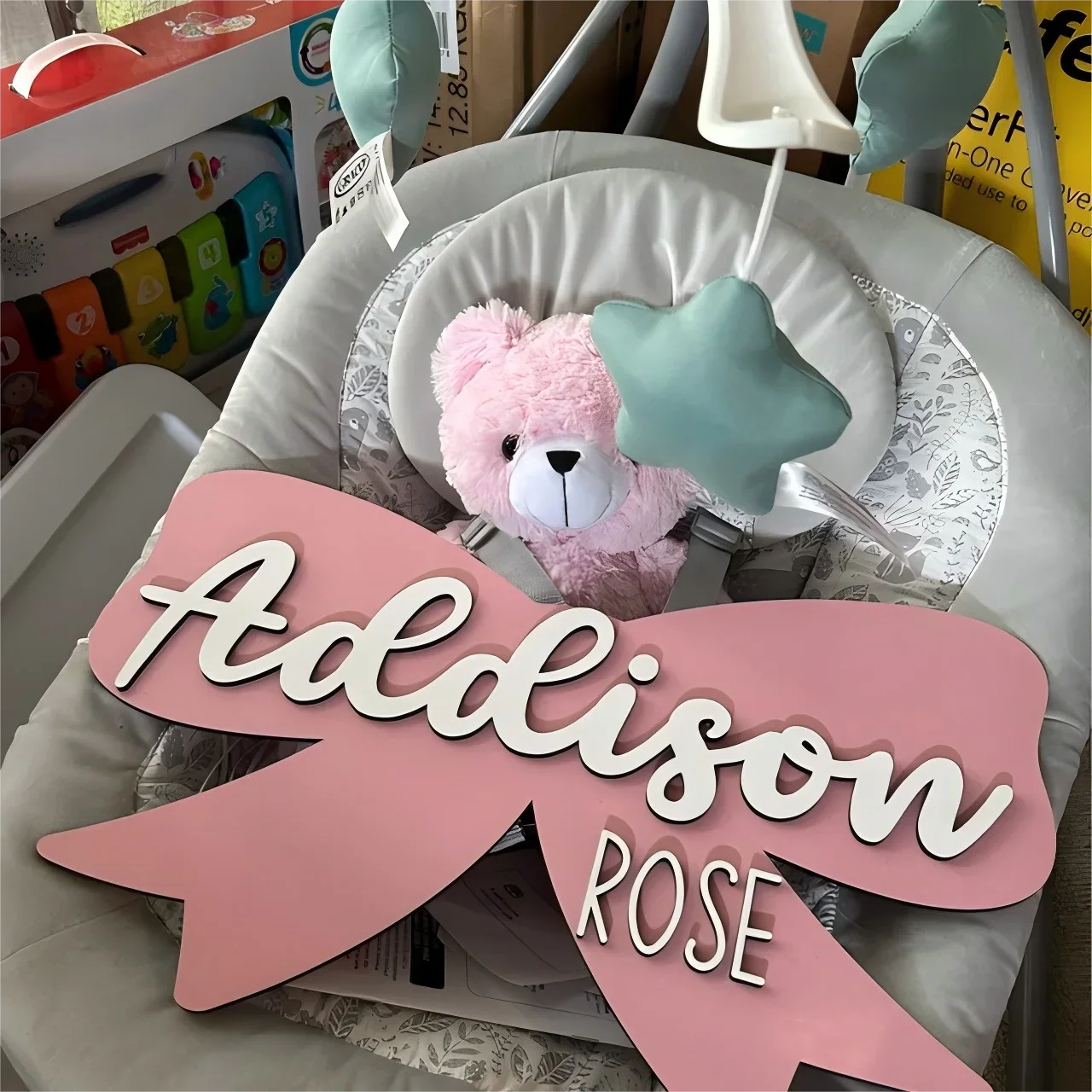 Wood baby name sign with pink bow, personalized nursery decor.