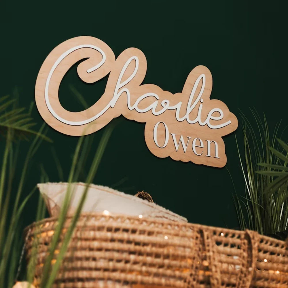 Customized wood baby name sign with bow decor for nursery room wall.