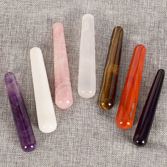 Natural stone crystal face massagers in various colors on a textured background.