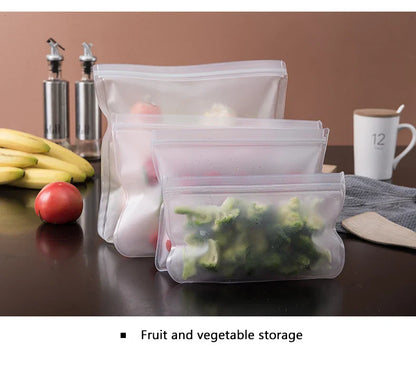 Set of reusable silicone food storage bags in three sizes containing fresh fruits and vegetables on kitchen counter