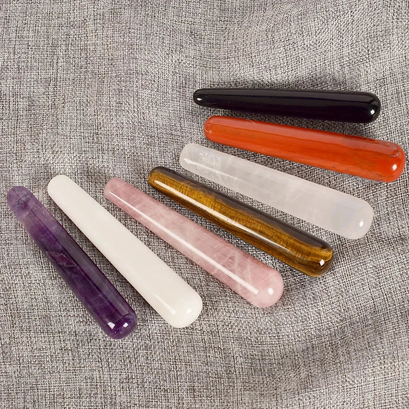 Natural crystal face massagers in various colors on fabric background.