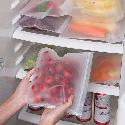 Reusable silicone food storage bags with leakproof zip seal holding fresh tomatoes in refrigerator