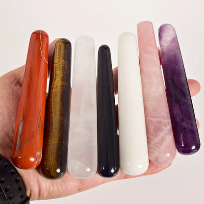 Assorted crystal face massagers in various colors held in a hand.