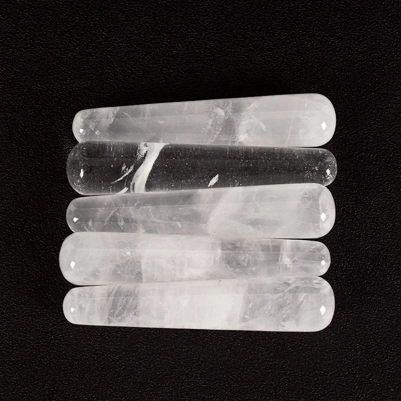 Natural rose quartz crystal face massager sticks on black background.