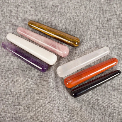 Crystal face massager stones in various colors on a gray fabric background.