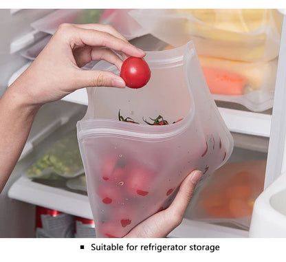 Reusable silicone food storage bag holding cherry tomatoes being placed in refrigerator
