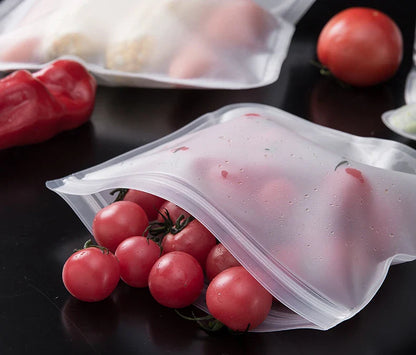 Reusable silicone food storage bags with zip seal holding cherry tomatoes on black surface