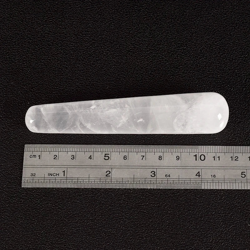 Rose quartz crystal face massager with ruler for size reference.