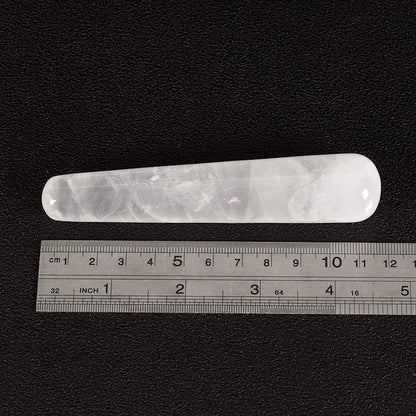 Rose quartz crystal face massager with ruler for size reference.