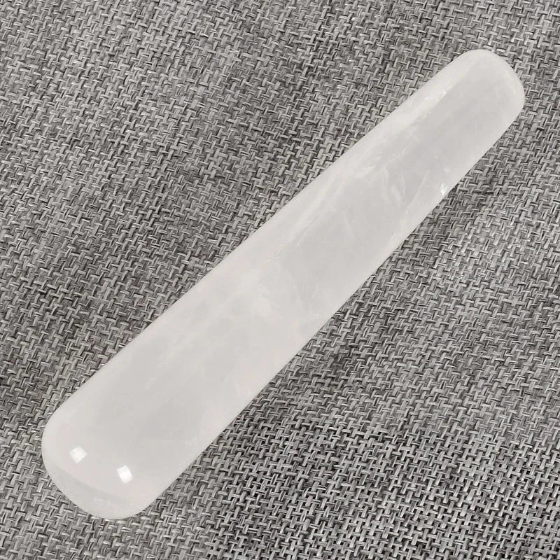 Natural rose quartz crystal face massager on a woven fabric background.