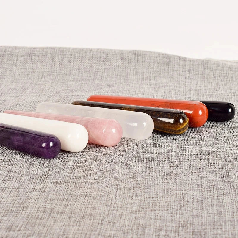 Natural stone crystal face massagers in assorted colors on fabric.