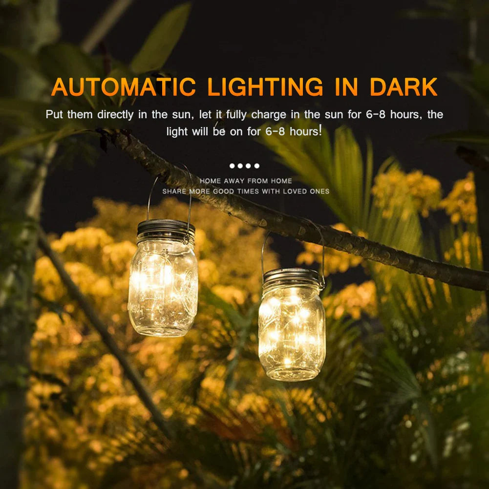 Solar mason jar lights hanging on tree branch illuminate garden at night.