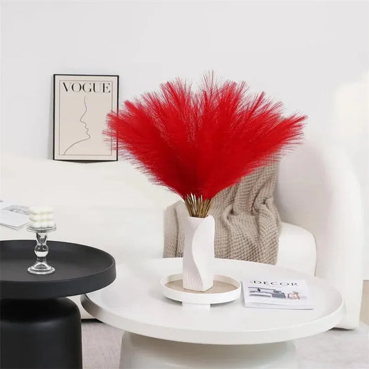 Vibrant red faux pampas grass centerpiece on modern white table.