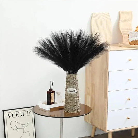 Artificial black pampas grass in a vase, displayed on a modern table next to a dresser.