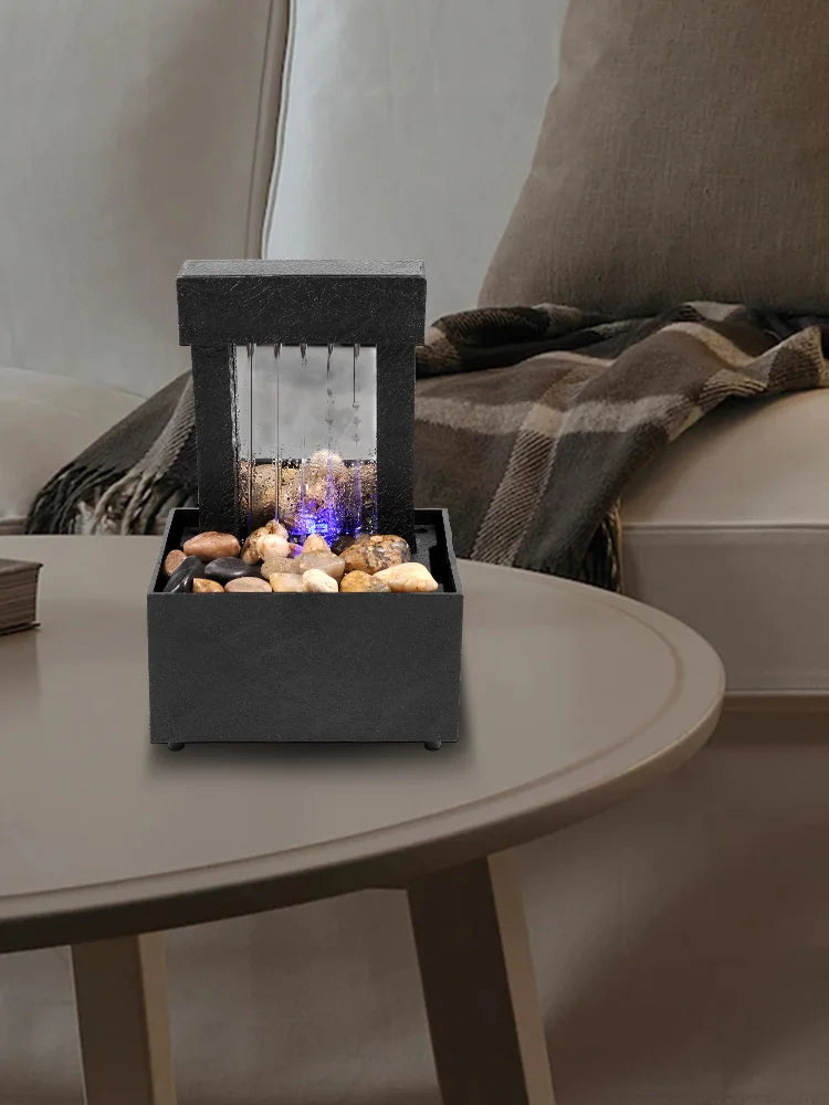 Mini indoor tabletop fountain with light on modern table for zen meditation ambiance.