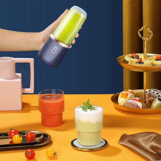 Portable electric mini blender for fresh fruit juice preparation, shown with various fruit arrangements.