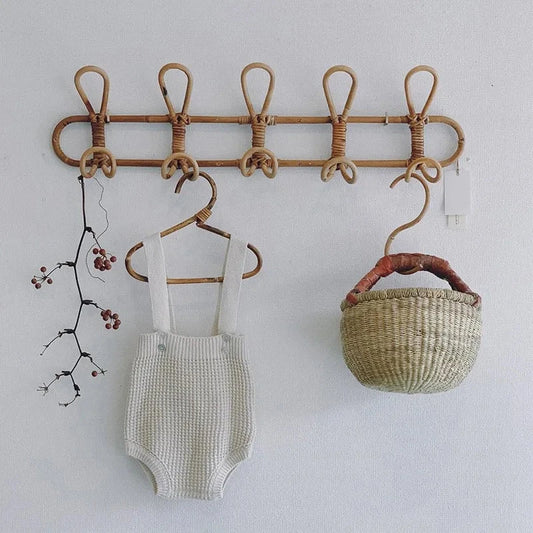 Rattan wall hooks for kids, holding baby clothes and a basket, eco-friendly nursery decor.