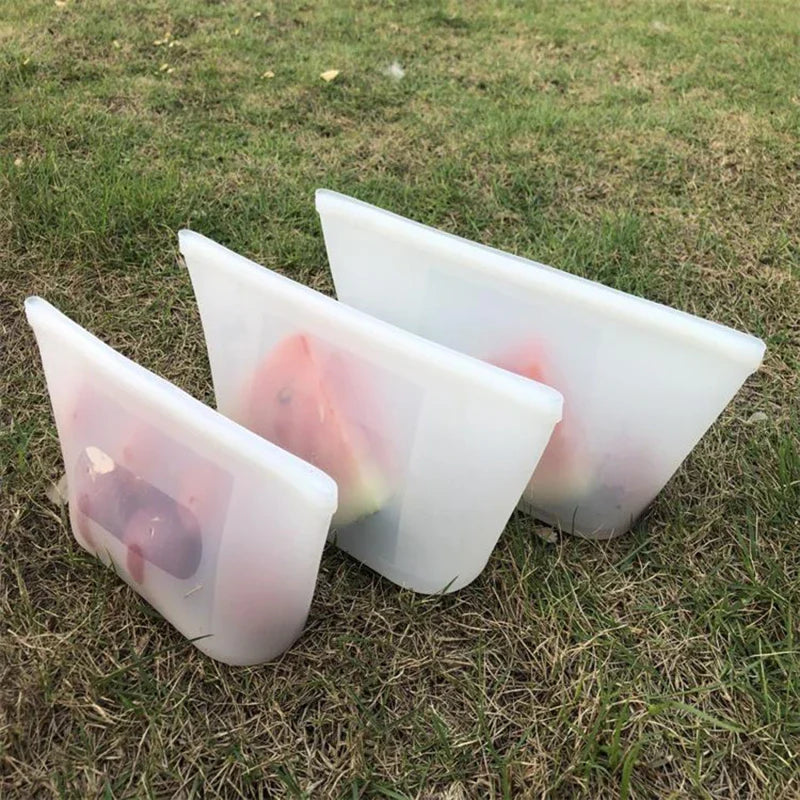 3-piece set of reusable silicone food storage bags on grass.