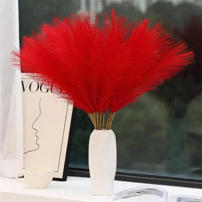 Red faux pampas grass in a white vase for elegant indoor decor.