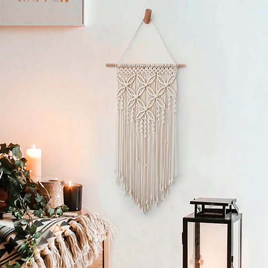 Macrame wall hanging tapestry with ethnic design, handcrafted from cotton and wooden stick, displayed as home decor in a cozy room setting.