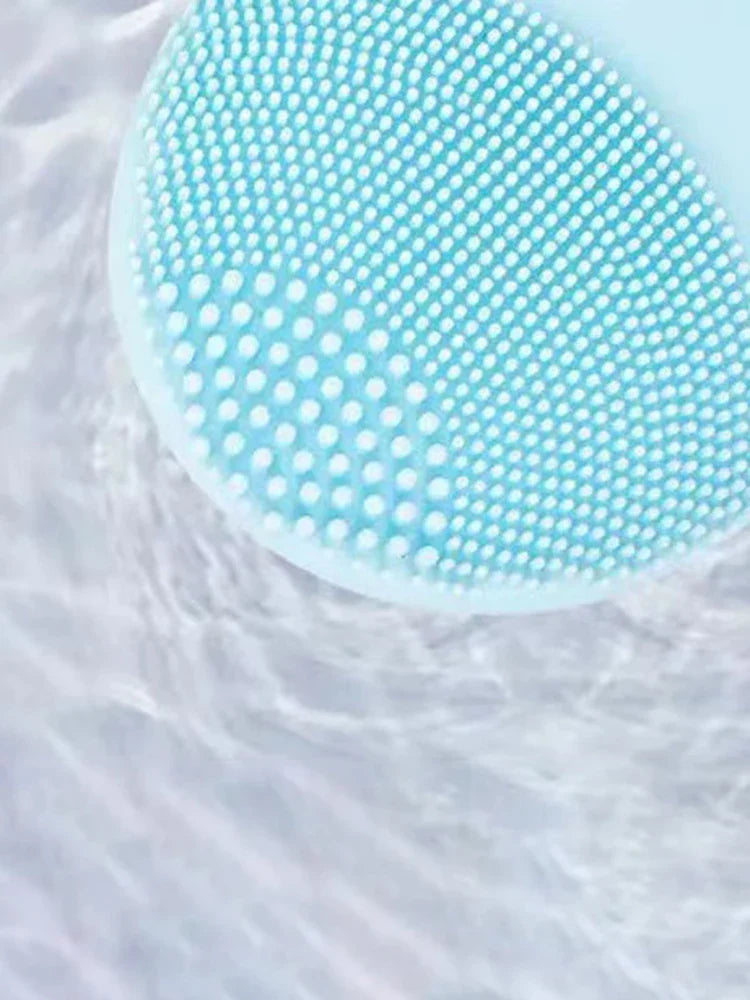 Close-up of a blue electric facial cleansing brush in water.