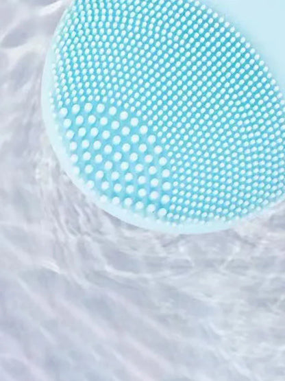 Close-up of a blue electric facial cleansing brush in water.