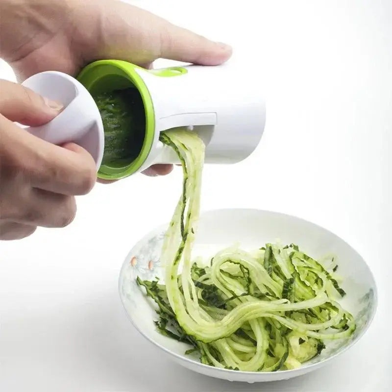 Handheld vegetable spiralizer creating zucchini noodles over a bowl.