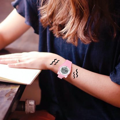 Kid wearing a pink fitness tracker watch with LED display.