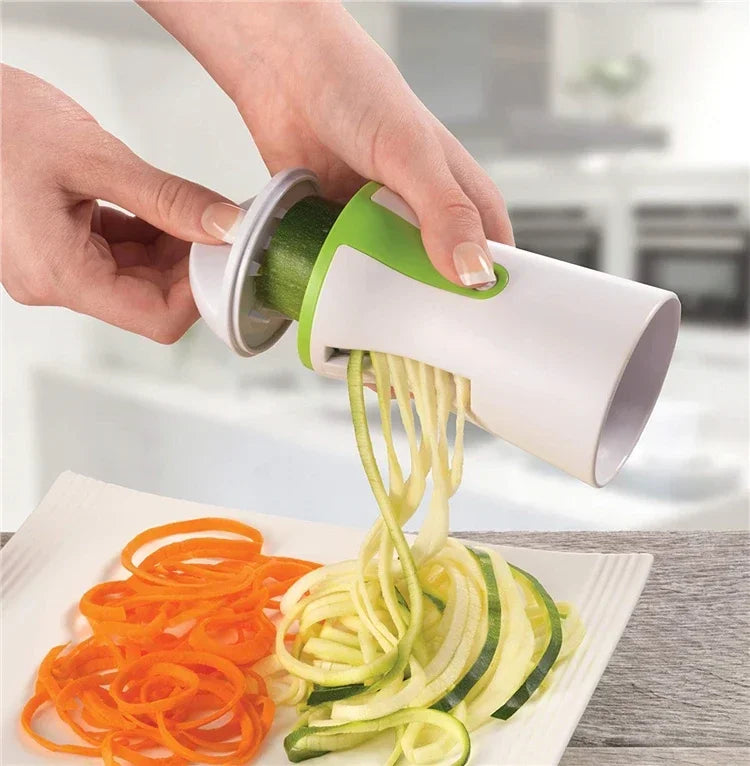 Vegetable spiralizer creating zucchini noodles with stainless steel blades in a kitchen setting.