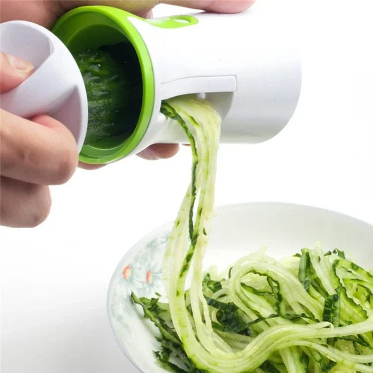 Handheld vegetable spiralizer creating zucchini noodles over a plate.