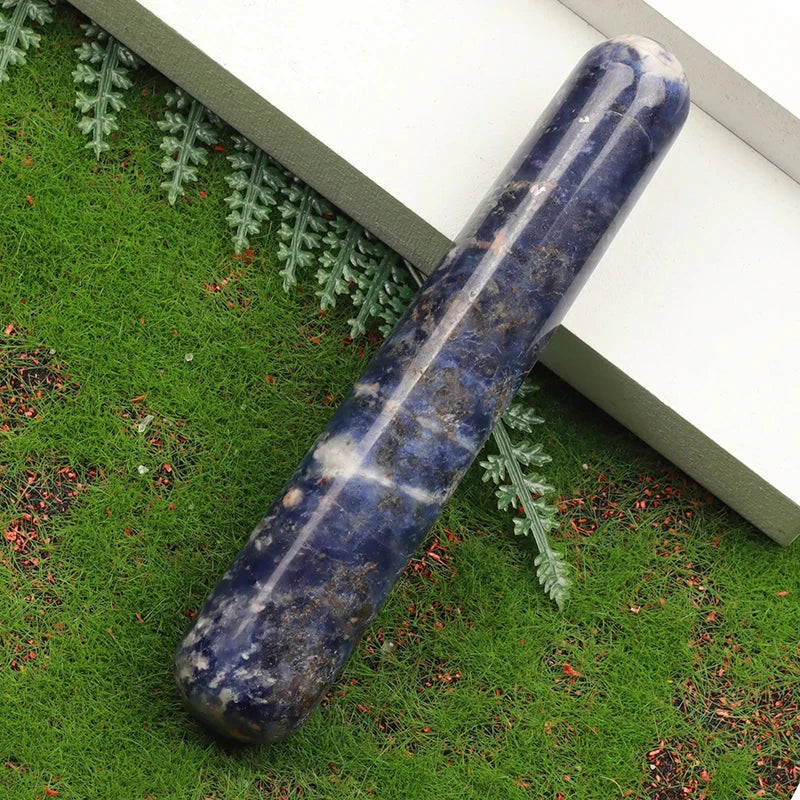 Natural stone crystal face massager on grass background.