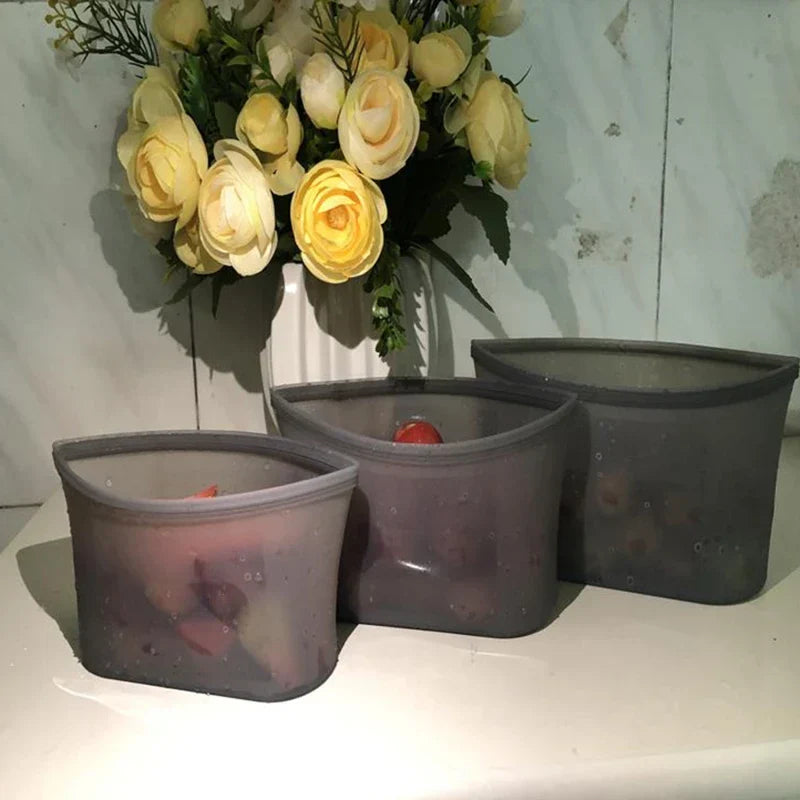 Set of three reusable silicone food storage bags on a countertop.