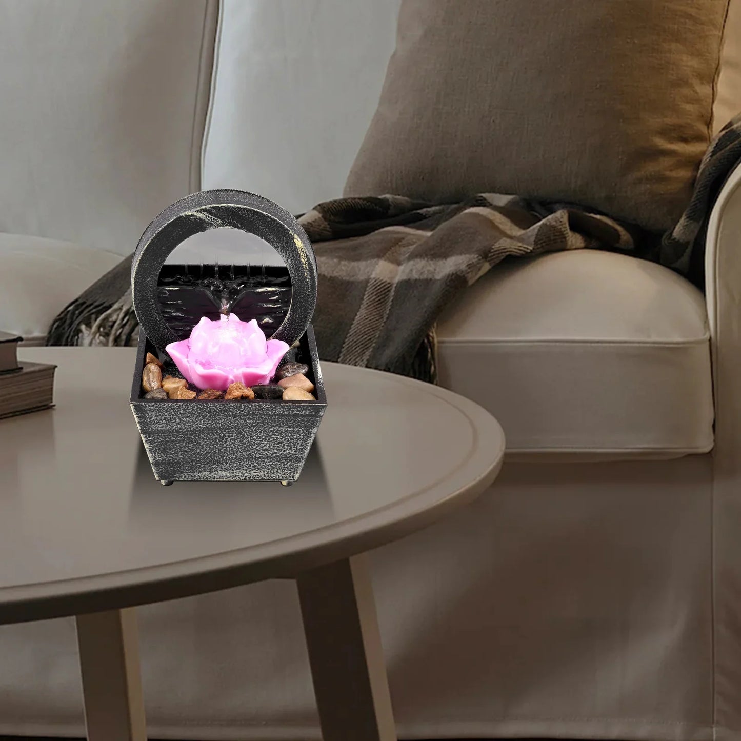 Tabletop fountain with light on a coffee table in a living room setting.
