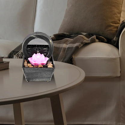 Tabletop fountain with light on a coffee table in a living room setting.
