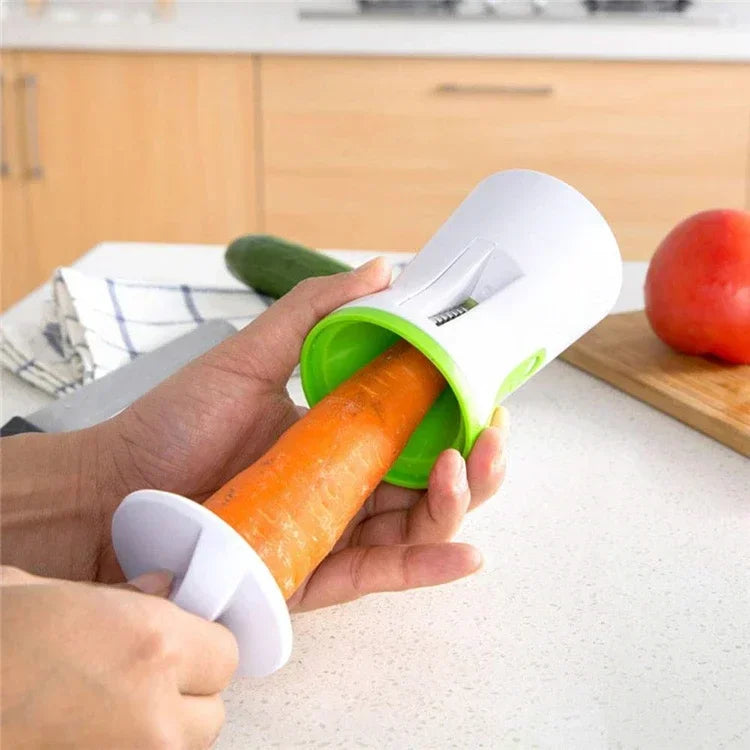 Hand using a vegetable spiralizer on a carrot in a kitchen setting.