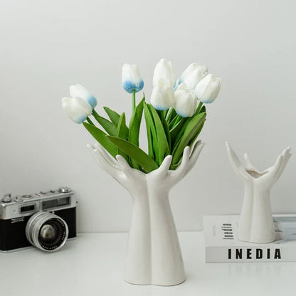 Modern ceramic vase shaped like hands holding a flower bouquet, ideal for tabletop decoration.