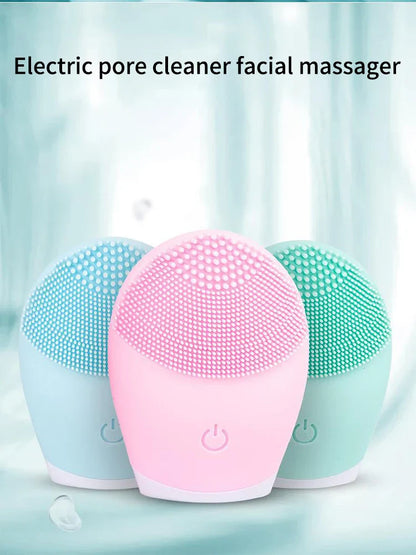 Electric facial cleansing brush in pink, blue, and green silicone with vibration massage feature.
